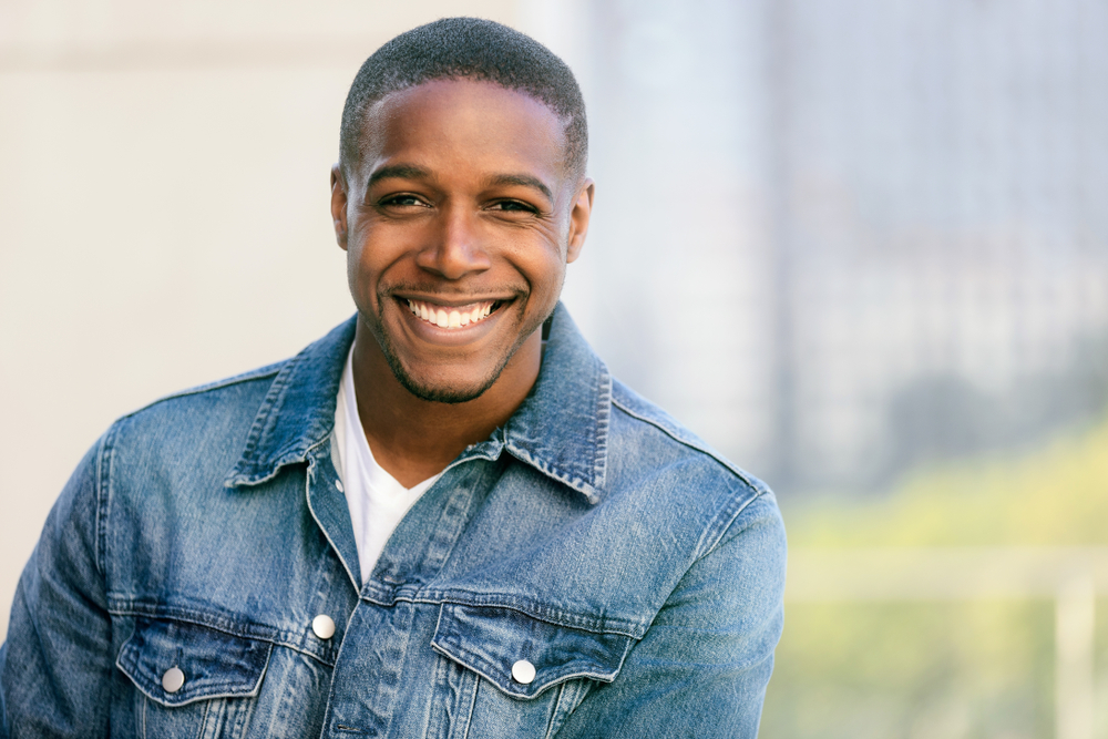 Black man smiling after restorative dental treatment in Urbandale, IA